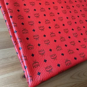 mcm red vinyl fabric with black mcm logo pattern on it